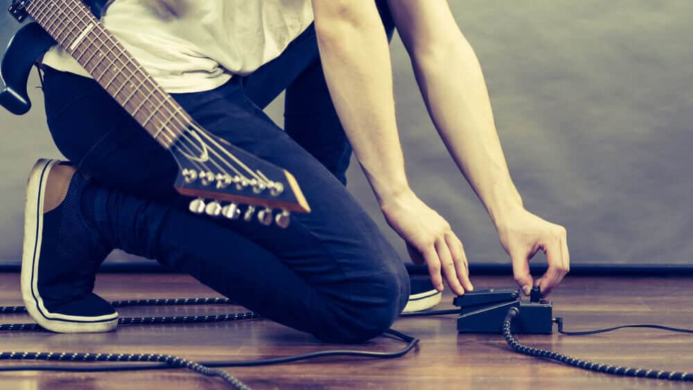 Guitar player configure and setting the loop pedal on the floor.